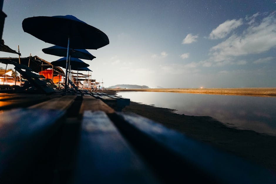 A tranquil beach view at twilight with rows of beach umbrellas and a serene ocean backdrop.